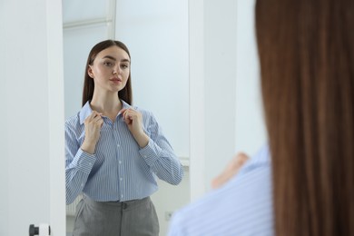 Photo of Beautiful woman looking at herself in mirror indoors
