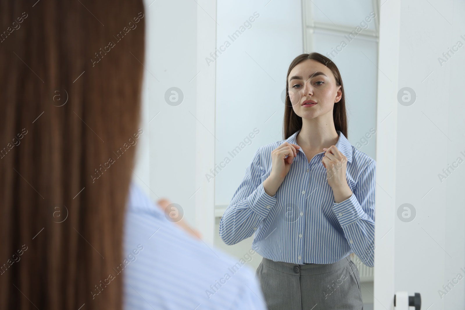 Beautiful woman looking at herself in mirror indoors Photo of Beautiful woman looking at herself in mirror indoors