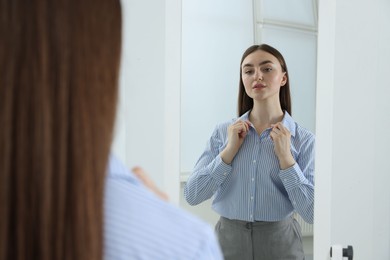 Photo of Beautiful woman looking at herself in mirror indoors
