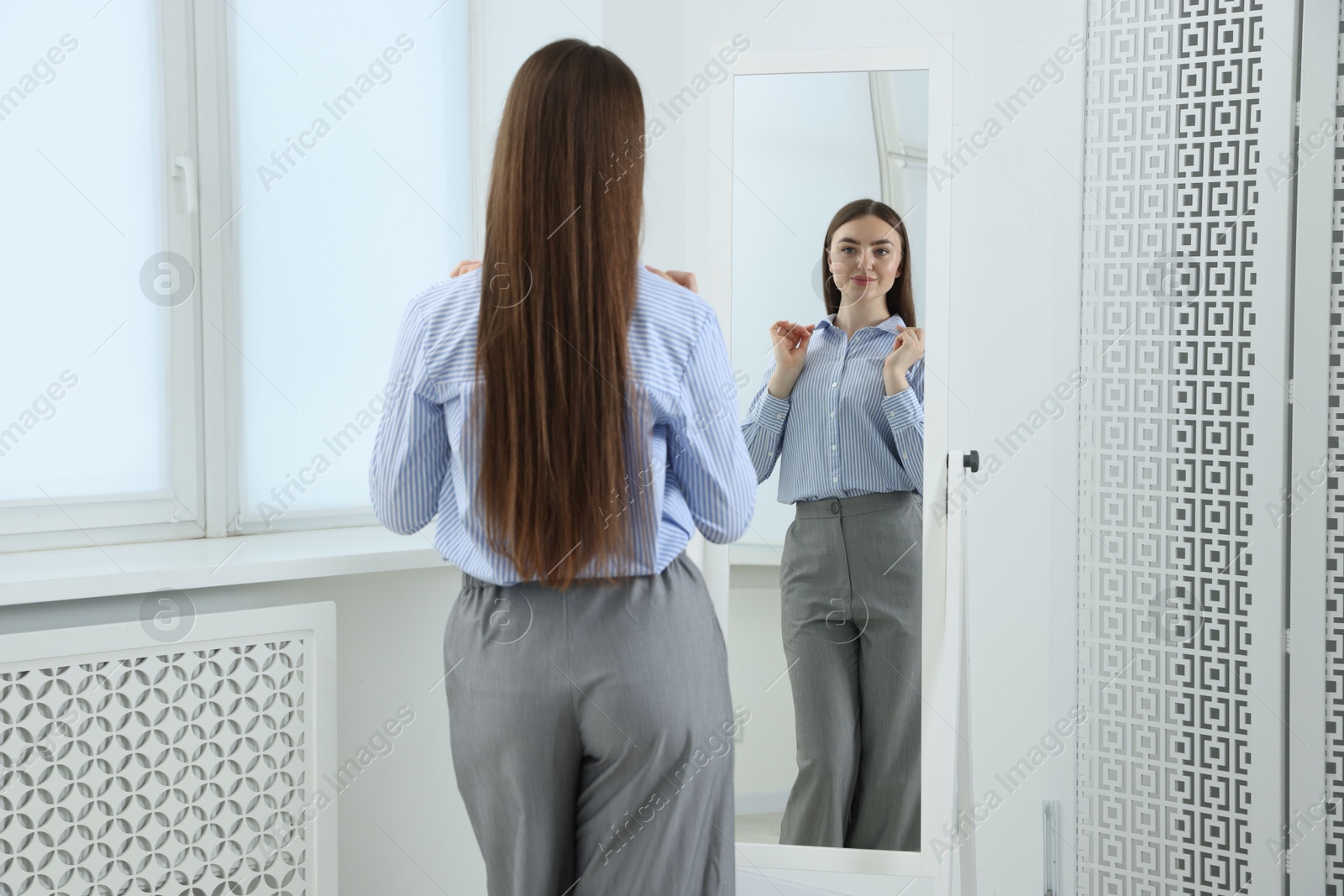 Beautiful woman looking at herself in mirror indoors Photo of Beautiful woman looking at herself in mirror indoors