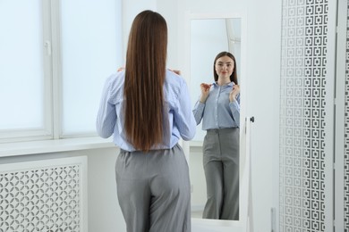 Photo of Beautiful woman looking at herself in mirror indoors