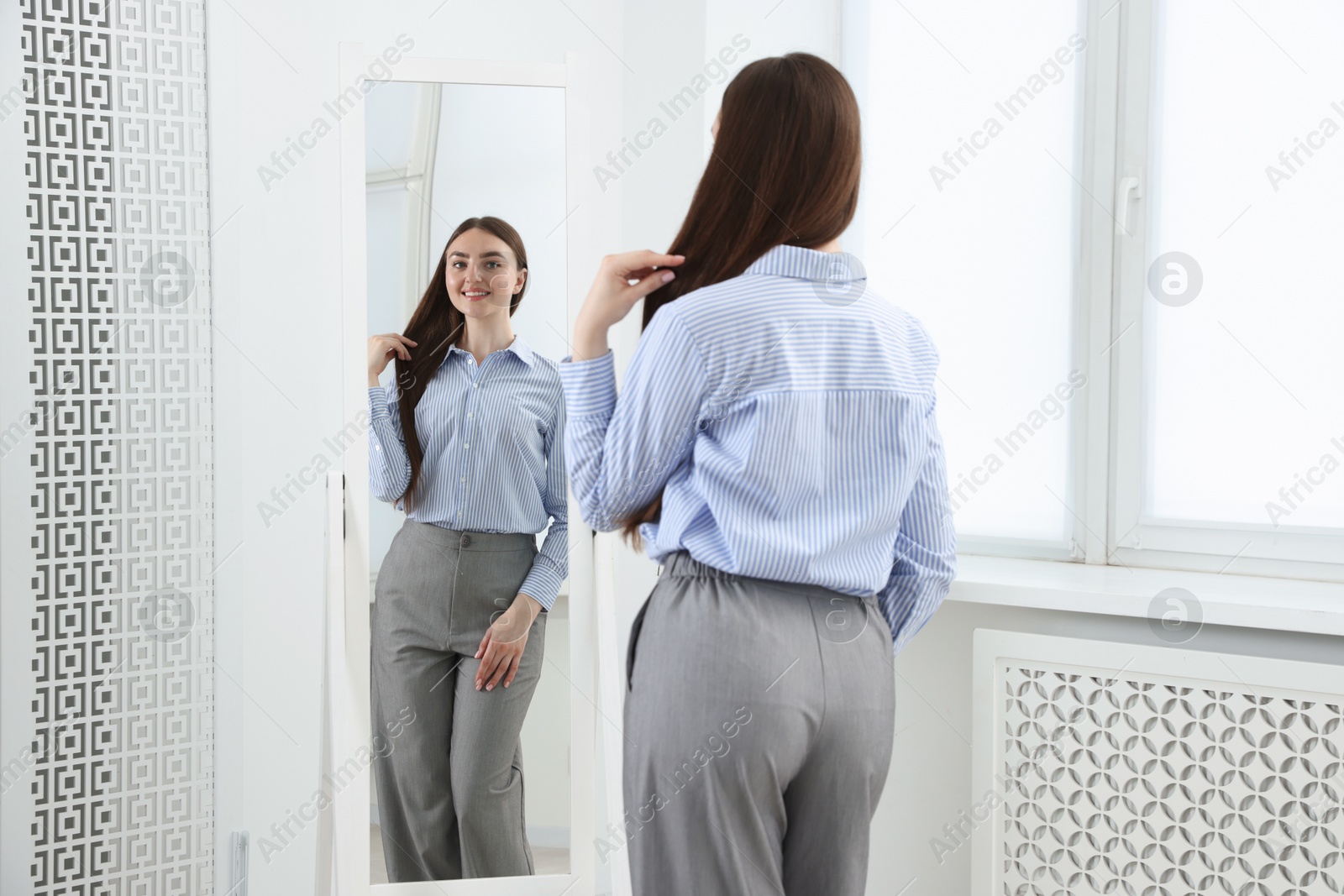 Beautiful woman looking at herself in mirror indoors Photo of Beautiful woman looking at herself in mirror indoors