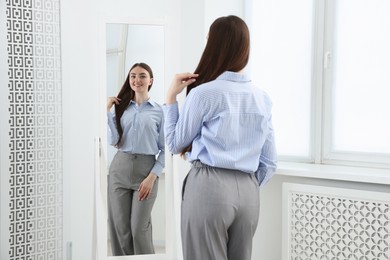 Photo of Beautiful woman looking at herself in mirror indoors