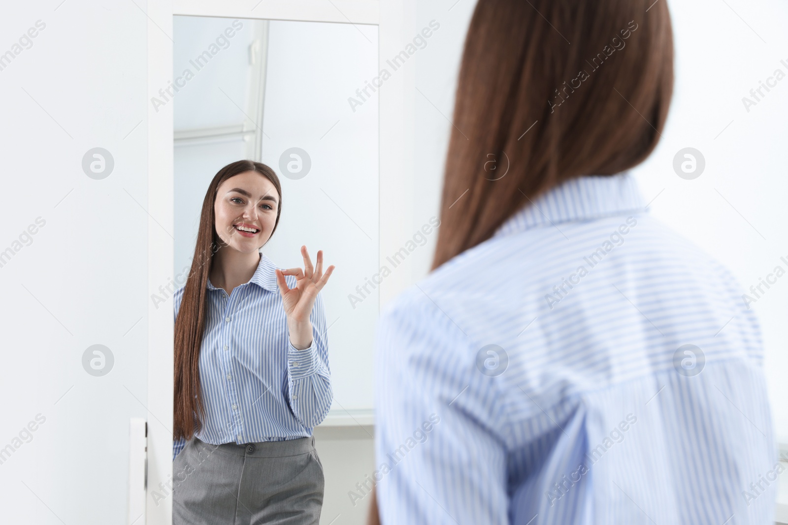 Beautiful woman looking at herself in mirror indoors Photo of Beautiful woman looking at herself in mirror indoors