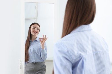 Photo of Beautiful woman looking at herself in mirror indoors
