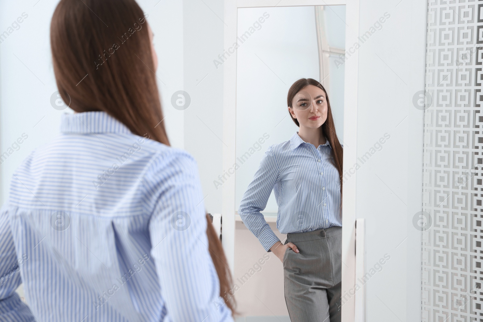 Beautiful woman looking at herself in mirror indoors Photo of Beautiful woman looking at herself in mirror indoors