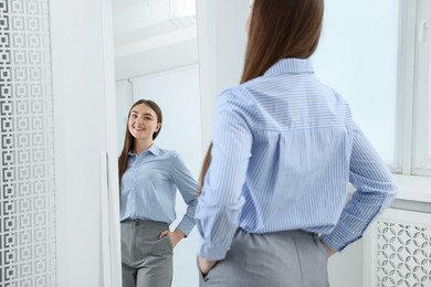 Photo of Beautiful woman looking at herself in mirror indoors