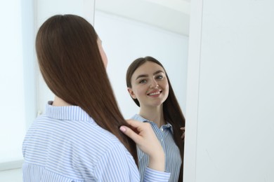 Photo of Beautiful woman looking at herself in mirror indoors