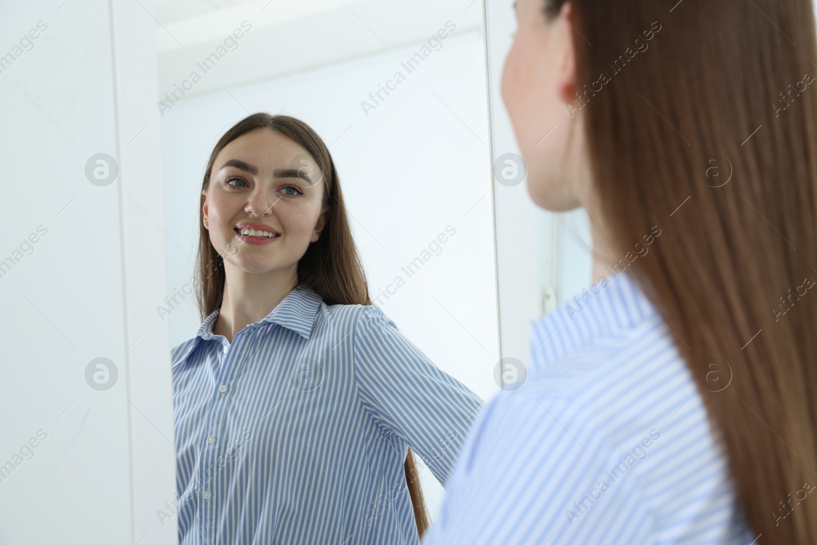 Beautiful woman looking at herself in mirror indoors Photo of Beautiful woman looking at herself in mirror indoors