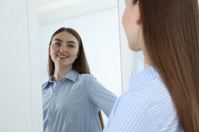 Photo of Beautiful woman looking at herself in mirror indoors