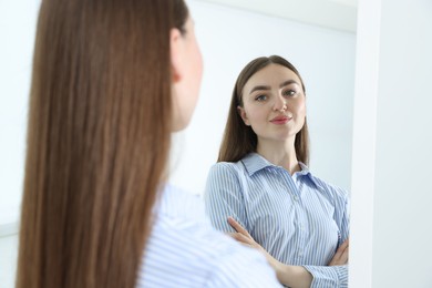 Photo of Beautiful woman looking at herself in mirror indoors