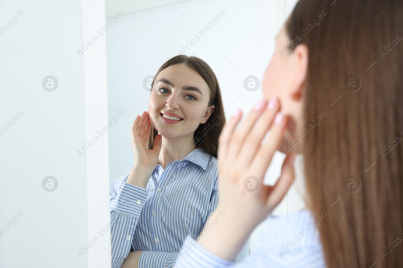 Beautiful woman looking at herself in mirror indoors Photo of Beautiful woman looking at herself in mirror indoors