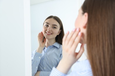 Photo of Beautiful woman looking at herself in mirror indoors