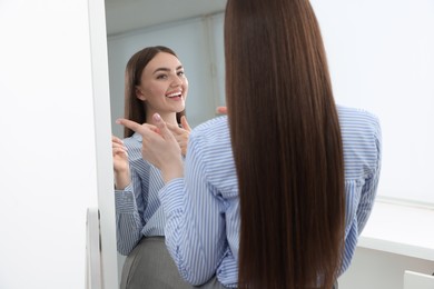 Photo of Beautiful woman looking at herself in mirror indoors