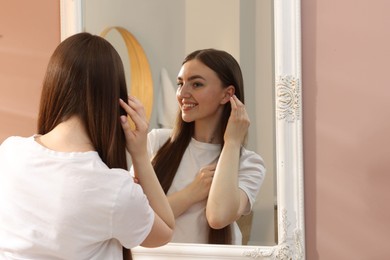 Photo of Beautiful woman looking at herself in mirror indoors