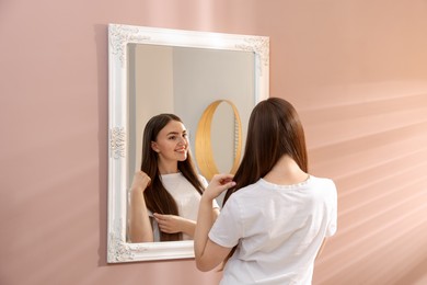Photo of Beautiful woman looking at herself in mirror indoors