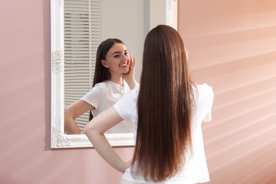 Photo of Beautiful woman looking at herself in mirror indoors