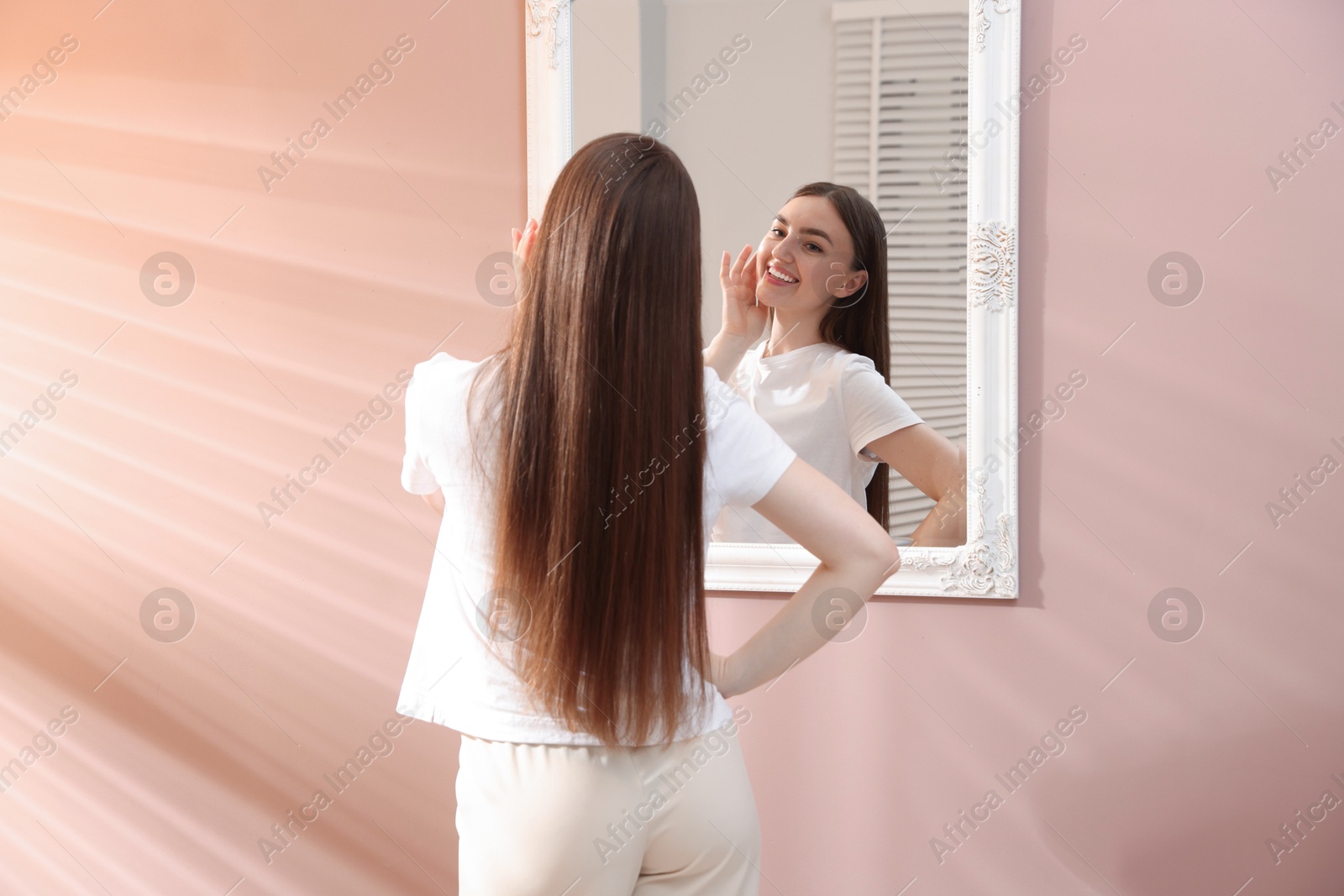Beautiful woman looking at herself in mirror indoors Photo of Beautiful woman looking at herself in mirror indoors