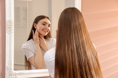 Photo of Beautiful woman looking at herself in mirror indoors