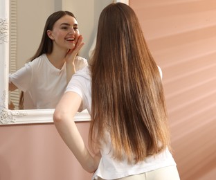 Photo of Beautiful woman looking at herself in mirror indoors