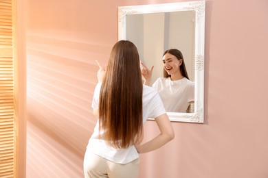 Photo of Beautiful woman looking at herself in mirror indoors