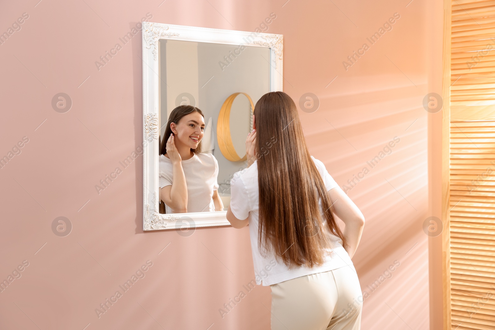 Beautiful woman looking at herself in mirror indoors Photo of Beautiful woman looking at herself in mirror indoors