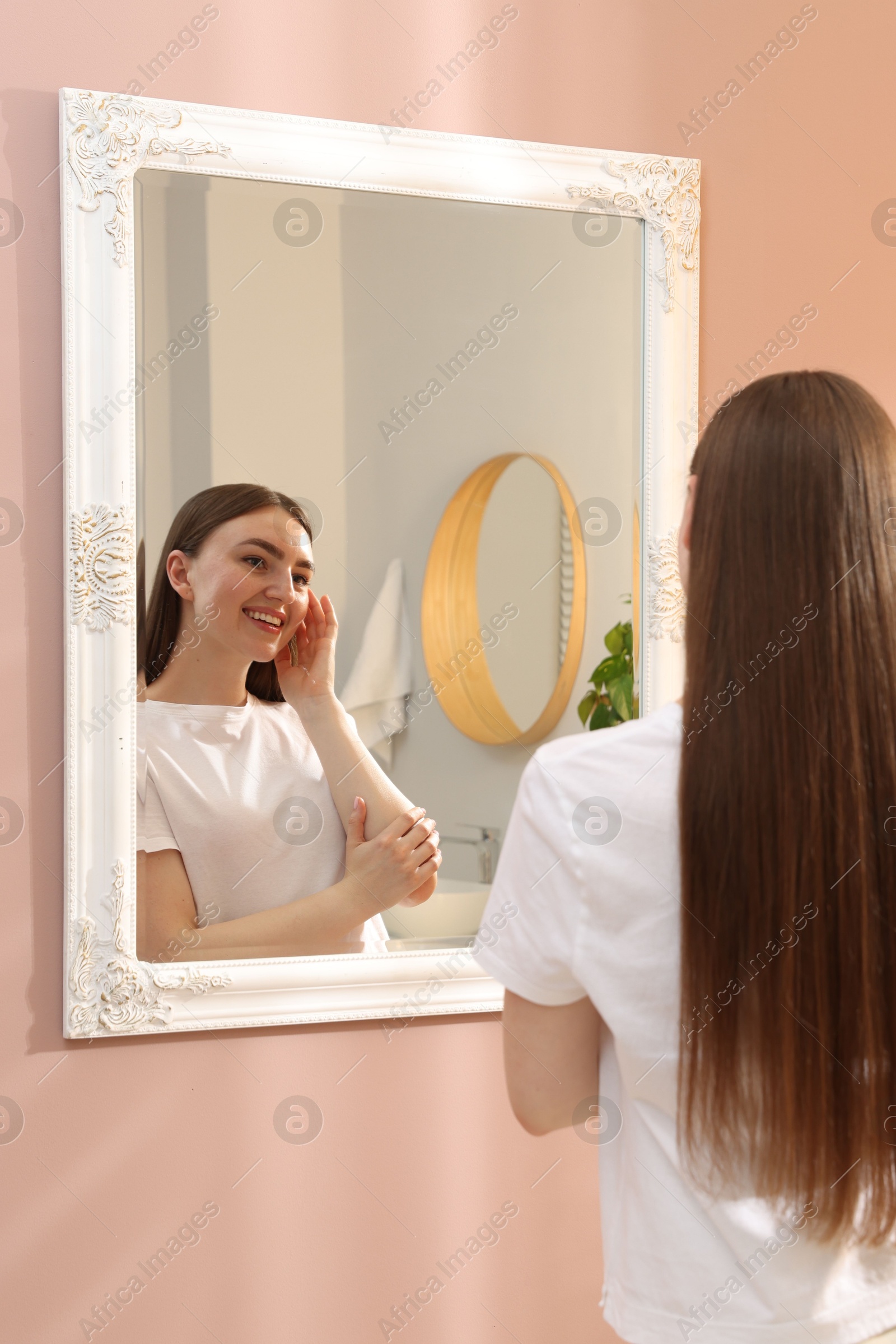 Beautiful woman looking at herself in mirror indoors Photo of Beautiful woman looking at herself in mirror indoors