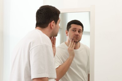 Photo of Handsome man looking at himself in mirror indoors