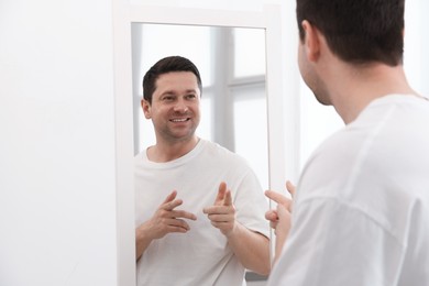 Photo of Handsome man looking at himself in mirror indoors