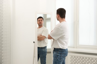 Photo of Handsome man looking at himself in mirror indoors