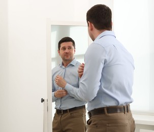 Photo of Handsome man looking at himself in mirror indoors