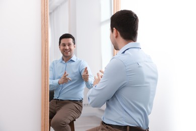 Photo of Handsome man looking at himself in mirror indoors