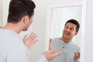 Photo of Handsome man looking at himself in mirror indoors