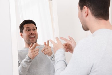 Photo of Handsome man looking at himself in mirror indoors