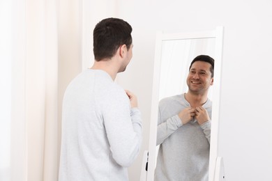 Photo of Handsome man looking at himself in mirror indoors