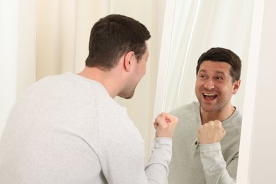 Photo of Handsome man looking at himself in mirror indoors