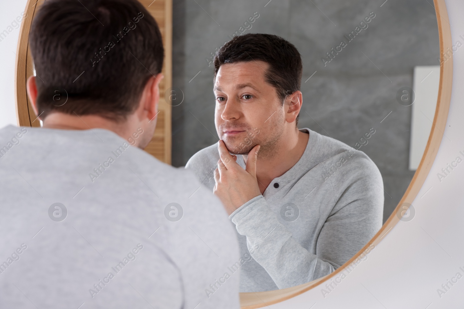 Handsome man looking at himself in mirror indoors Photo of Handsome man looking at himself in mirror indoors