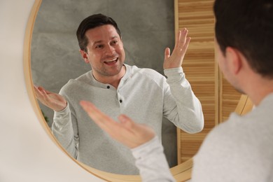 Photo of Handsome man looking at himself in mirror indoors