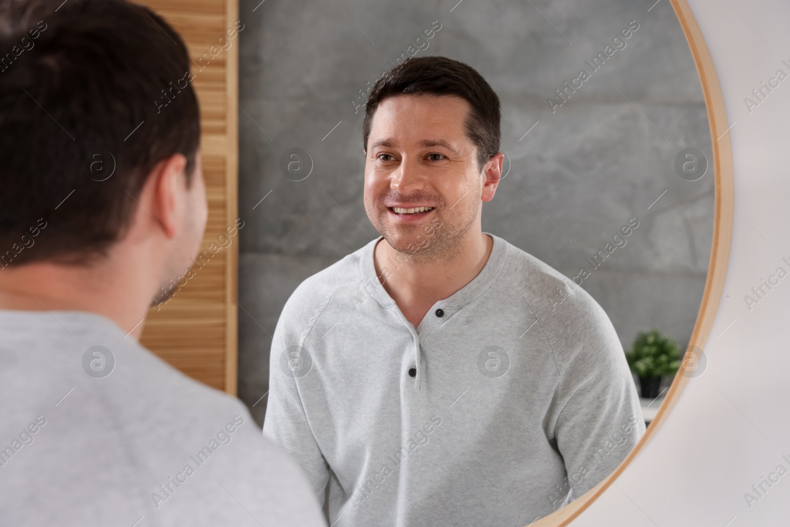 Handsome man looking at himself in mirror indoors Photo of Handsome man looking at himself in mirror indoors
