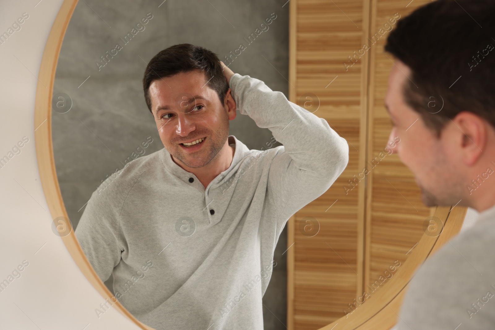Handsome man looking at himself in mirror indoors Photo of Handsome man looking at himself in mirror indoors
