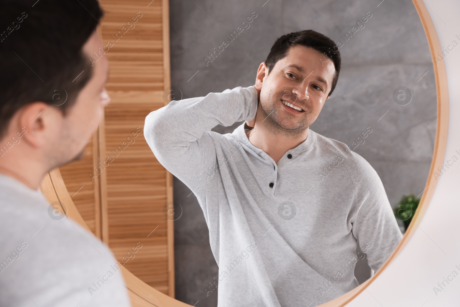 Handsome man looking at himself in mirror indoors Photo of Handsome man looking at himself in mirror indoors
