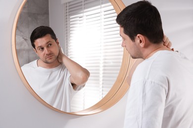 Photo of Handsome man looking at himself in mirror indoors