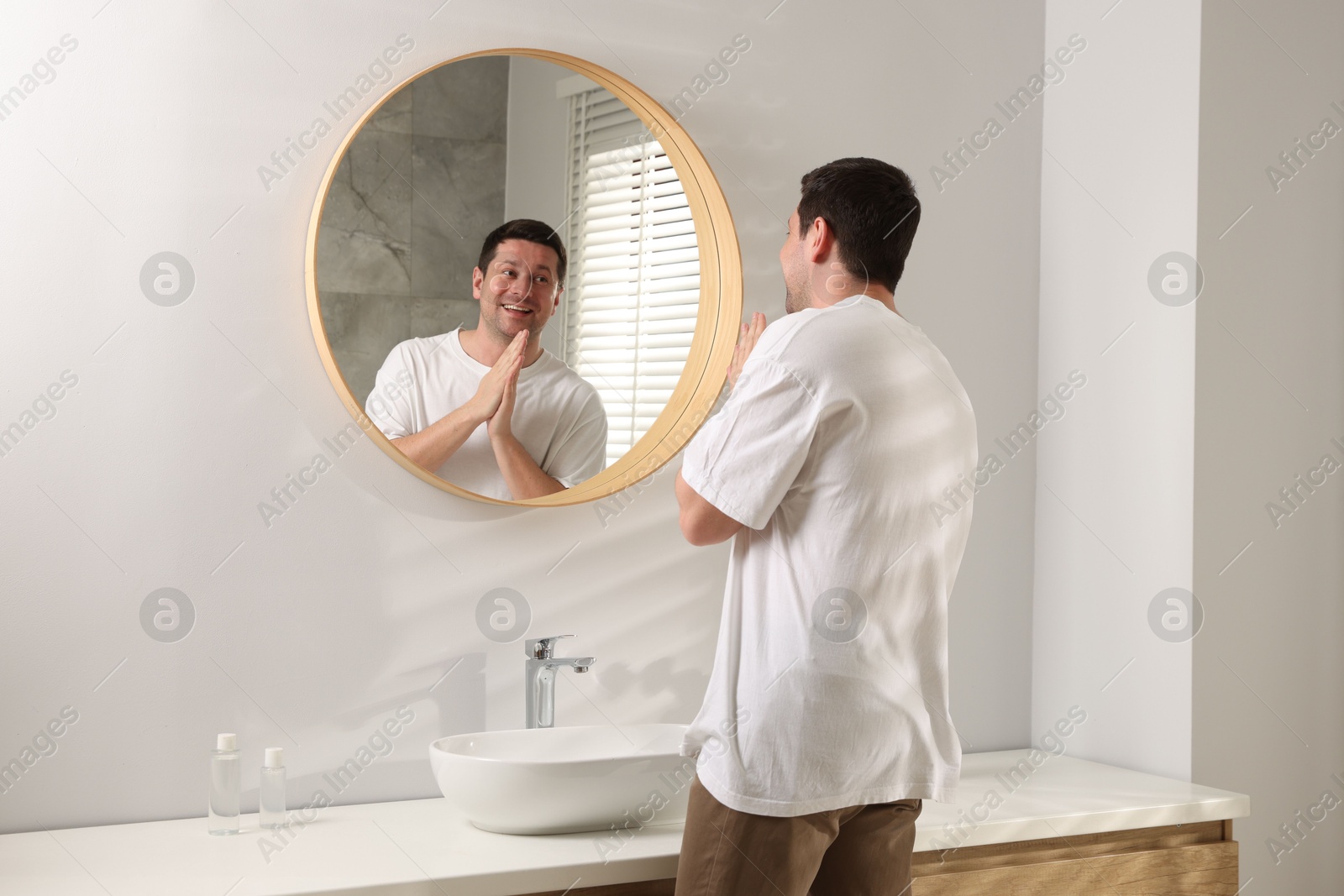 Handsome man looking at himself in mirror indoors Photo of Handsome man looking at himself in mirror indoors