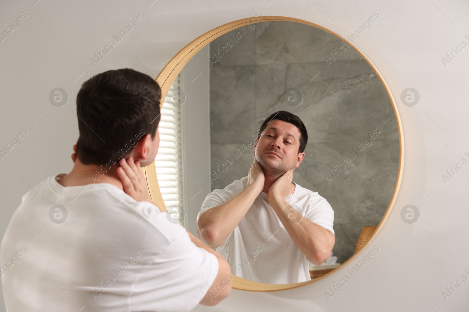 Handsome man looking at himself in mirror indoors Photo of Handsome man looking at himself in mirror indoors