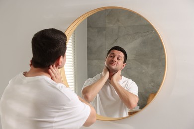 Photo of Handsome man looking at himself in mirror indoors