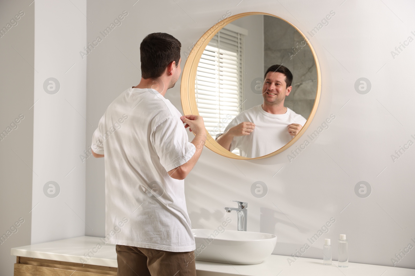 Handsome man looking at himself in mirror indoors Photo of Handsome man looking at himself in mirror indoors