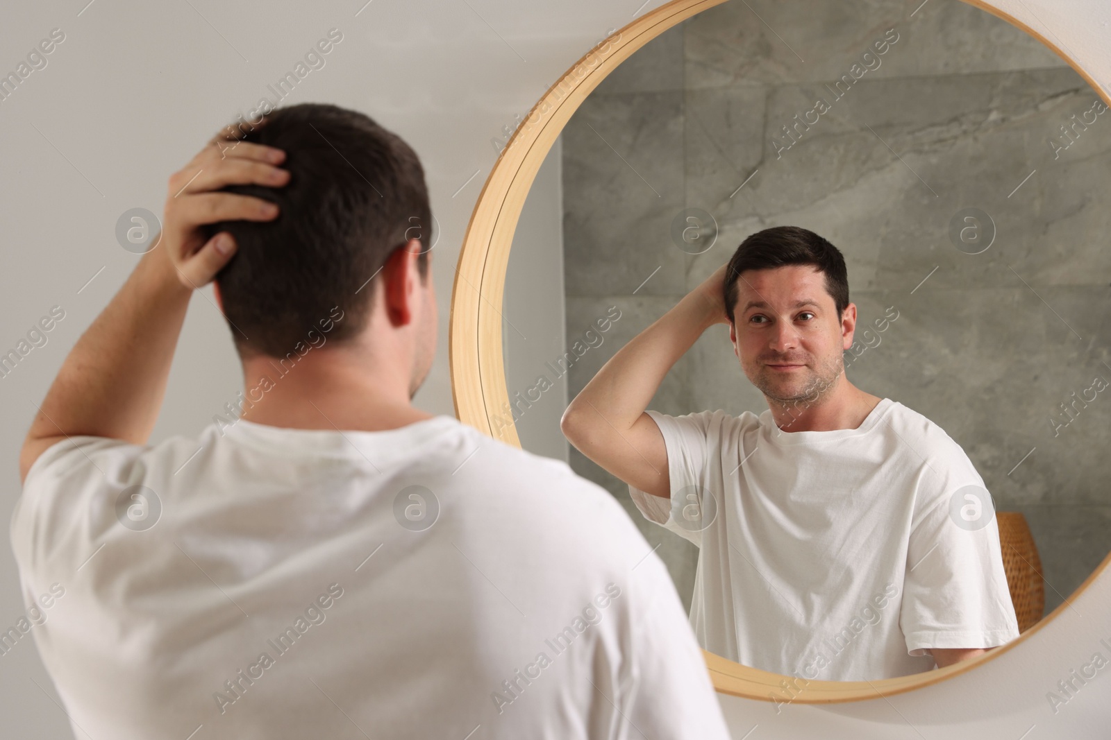Handsome man looking at himself in mirror indoors Photo of Handsome man looking at himself in mirror indoors