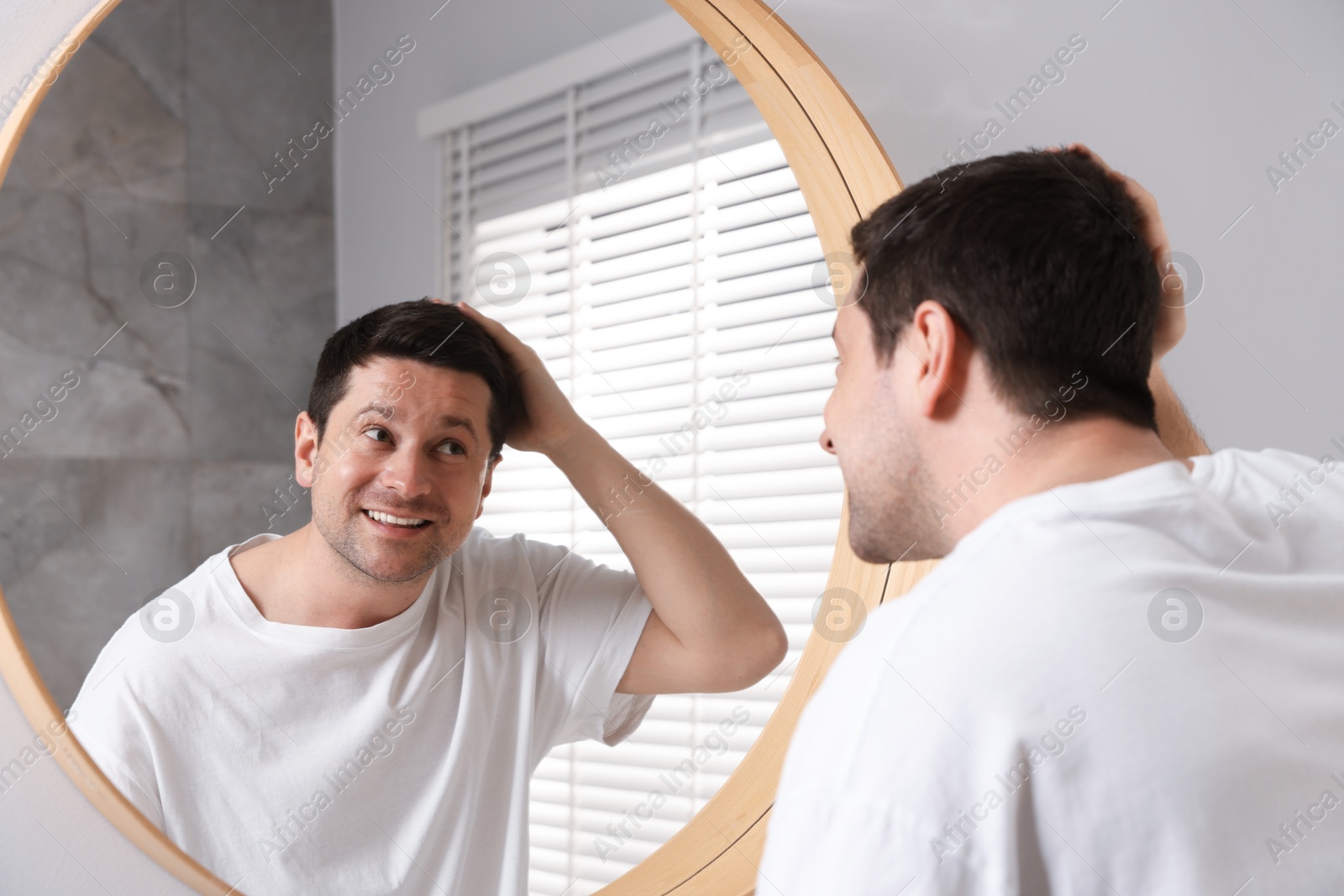 Handsome man looking at himself in mirror indoors Photo of Handsome man looking at himself in mirror indoors