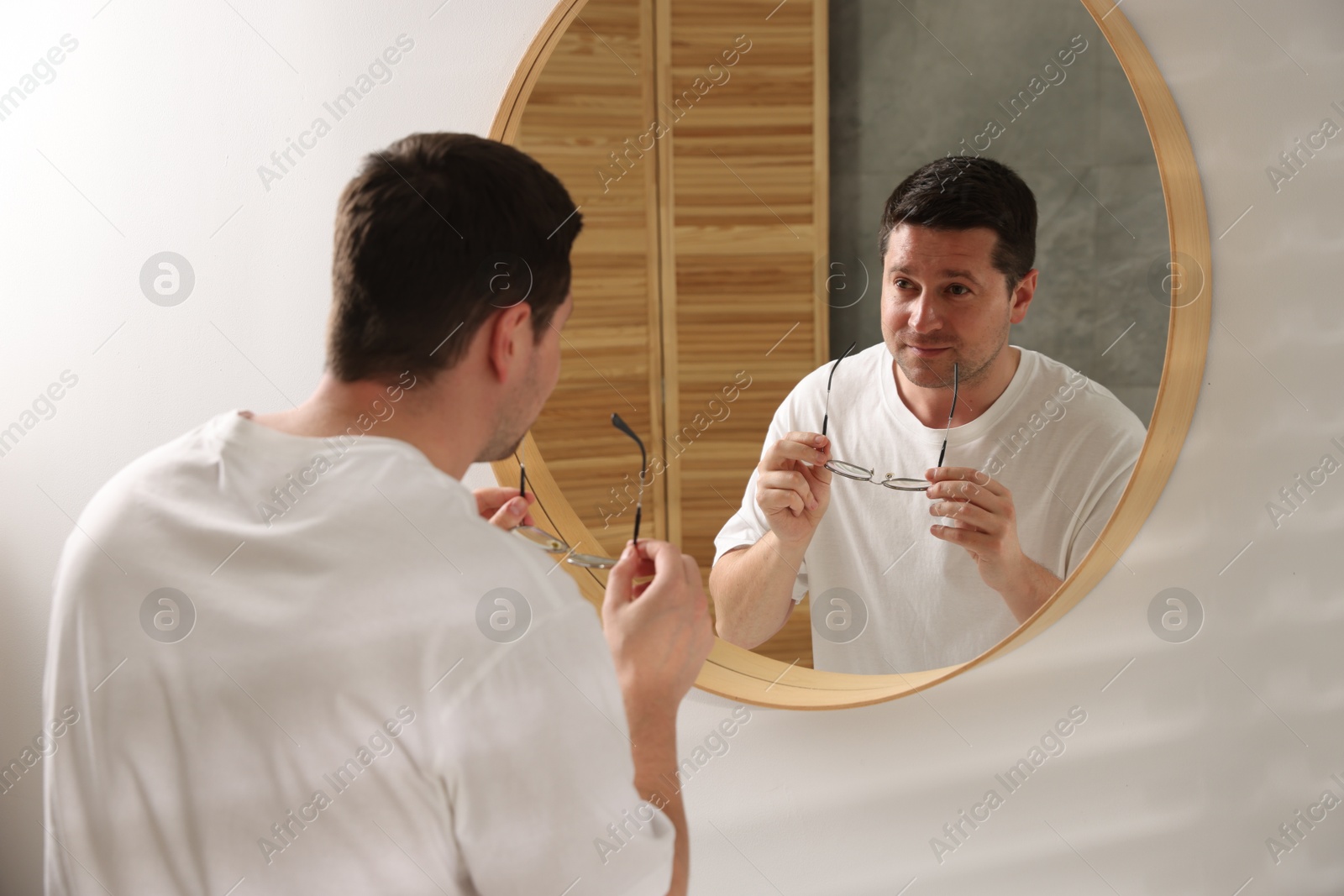 Handsome man looking at himself in mirror indoors Photo of Handsome man looking at himself in mirror indoors