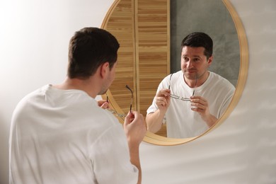 Photo of Handsome man looking at himself in mirror indoors
